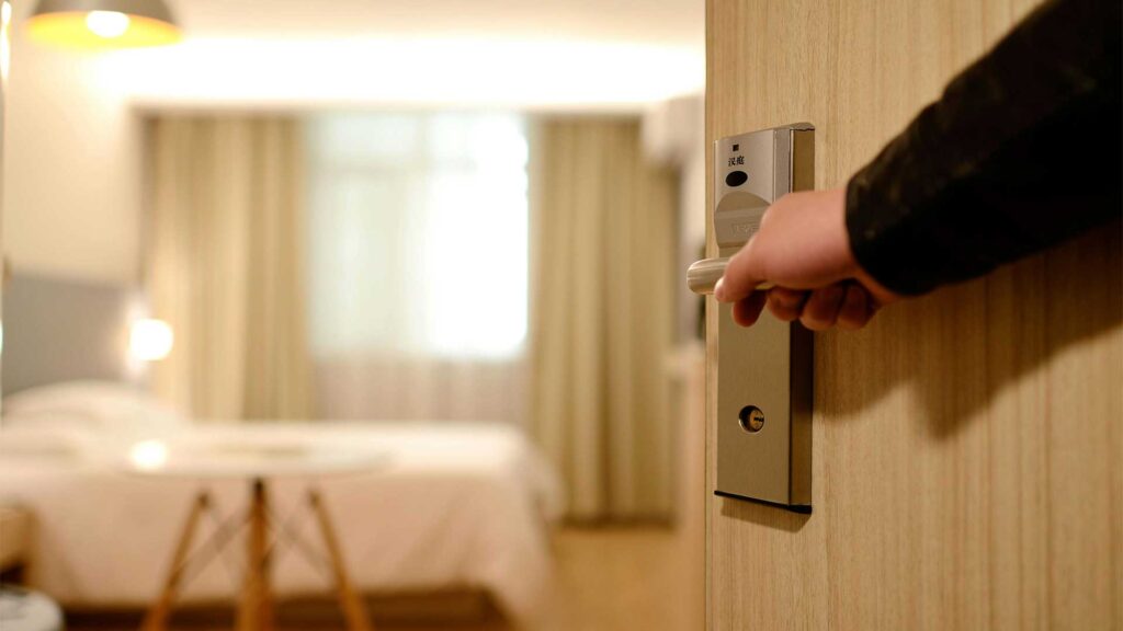 A man opening a hotel room door.